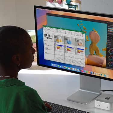 Mulher trabalhando em uma planilha do Excel em um Mac em uma mesa de escritório. A planilha do Excel é um rastreador de vendas do quarto trimestre. Ao fundo, uma janela do Pixelmator Pro.