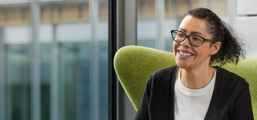 Karen sentada en una silla verde y sonriendo.