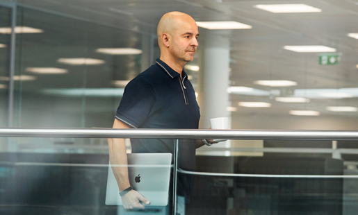 Roberto caminando y sosteniendo su laptop.