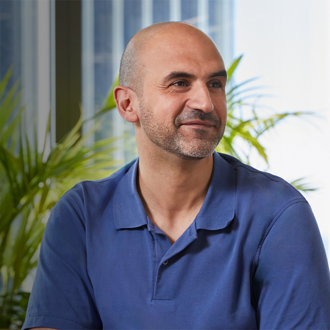 Ahmed sentado en un lugar cerrado, sonriendo y mirando fuera de cámara a su izquierda.