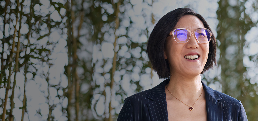 Ella frente a una pared cubierta de plantas, sonríe y ve hacia arriba.