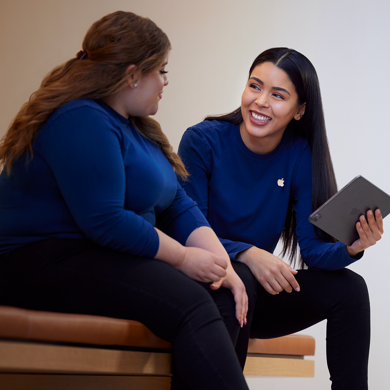 Carissa sostiene un iPad y habla con otra empleada de Apple Retail.