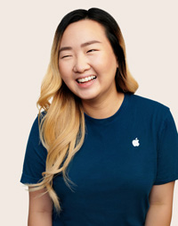 Empleada de Apple Retail con cabello largo sonríe a la cámara.