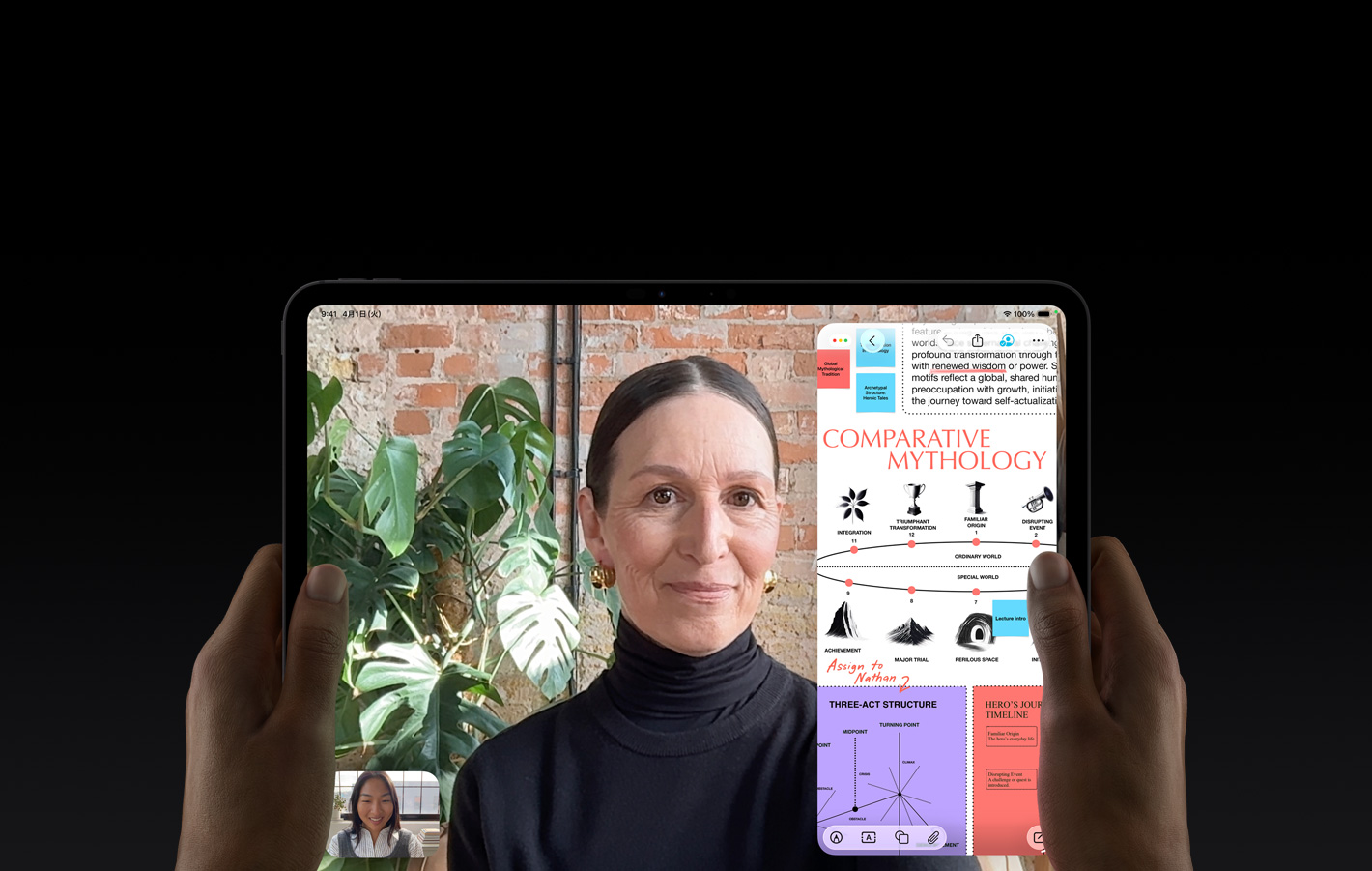 スペースブラックのiPad Proの前面の外観。左右の手で両端を持っている。四隅が丸みを帯びたブラックのディスプレイベゼル。ディスプレイに、FaceTimeでの会話がライブ翻訳されている様子が映し出されている。教育アプリには、テキスト、図表、手書きのメモが入った「Comparative Mythology」のプレゼンテーションが表示されている