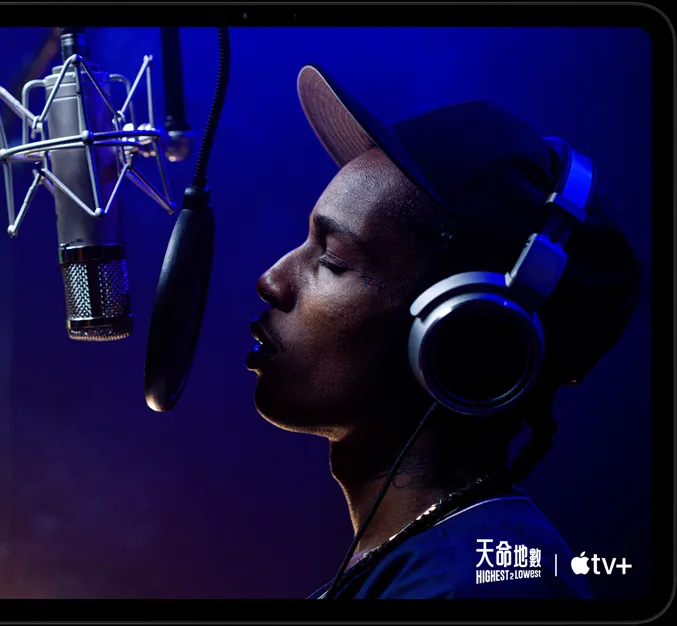橫向放置的太空黑 iPad Pro 機身正面，展示圓角設計，黑色顯示器邊框；螢幕顯示 TV app 正播放 Apple TV+ Original 原創電影《天命地數》(Highest 2 Lowest)，飾演 Yung Felon 的 ASAP Rocky 正拿著咪高風饒舌。