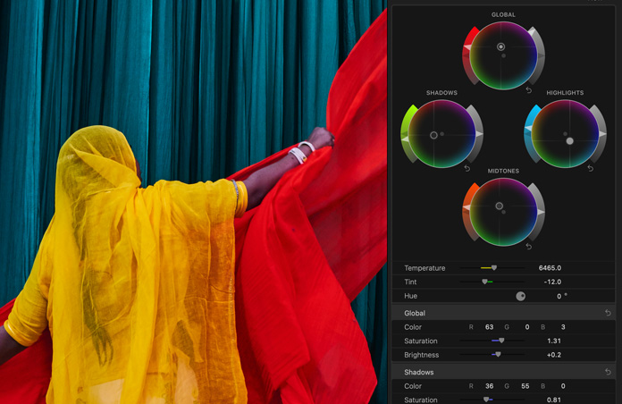 Screen showing a woman in a brightly coloured yellow sari with red scarves against a blue background, demo of colour grading tools