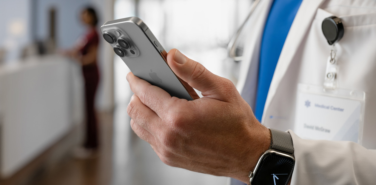 Die Hände einer ärztlichen Fachperson halten ein iPhone.