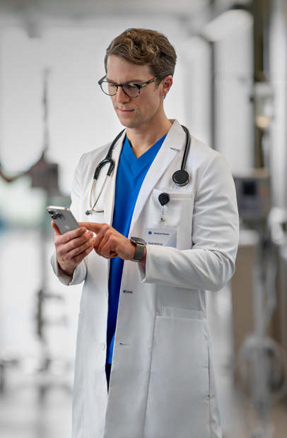 Eine Apple Watch am Handgelenk eines Arztes, auf der eine Medikamentenalarmmeldung von der Epic App angezeigt wird.