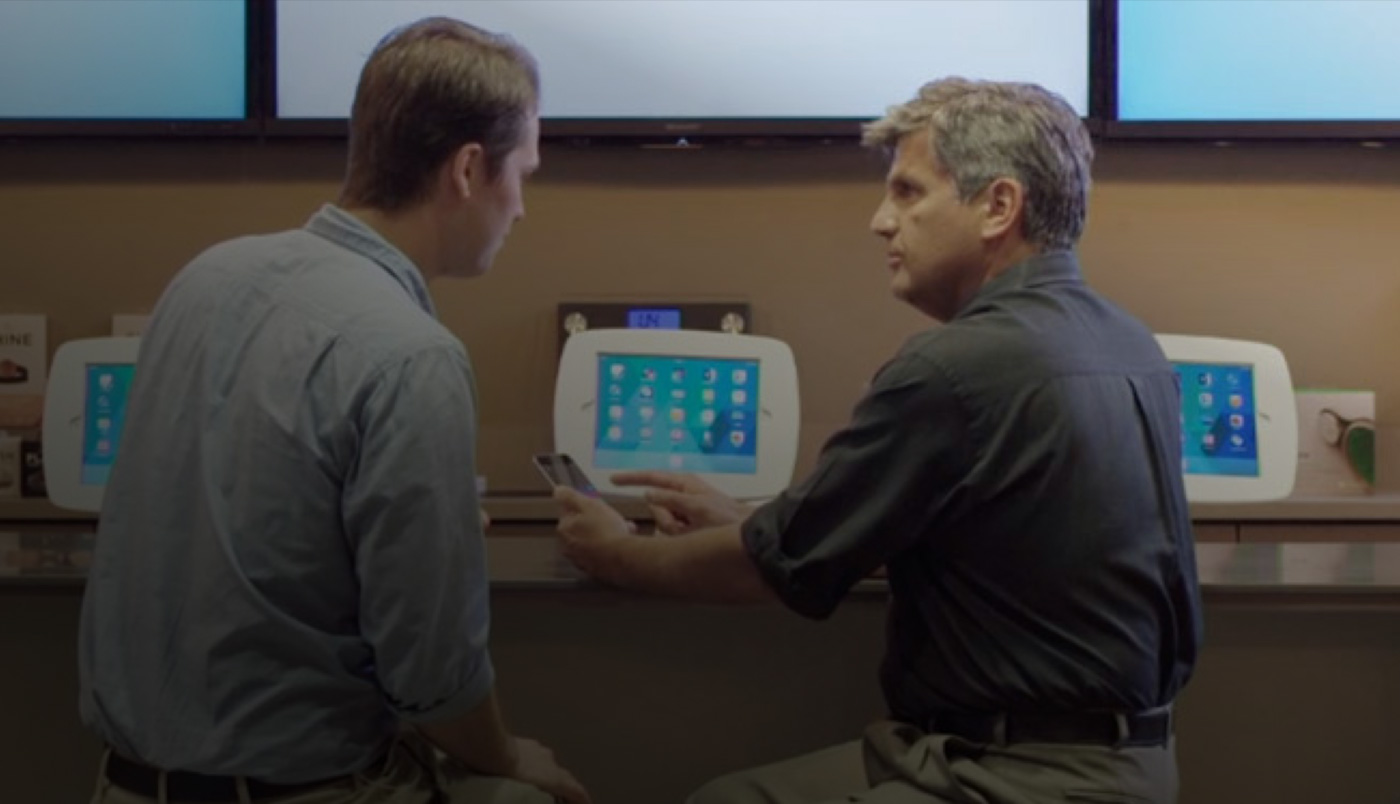 Zwei Männer sitzen an der O Bar und schauen auf ein iPhone Display.