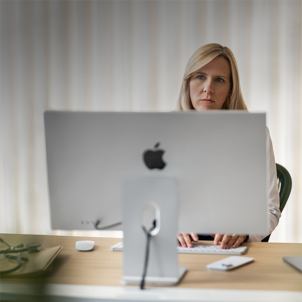 A provider looks at an iMac screen from behind her desk.