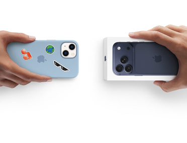 Hænder bytter iPhones. iPhone 13 med silikone-etui og klistermærker på bagsiden byttes for en ny iPhone 17 i æsken.