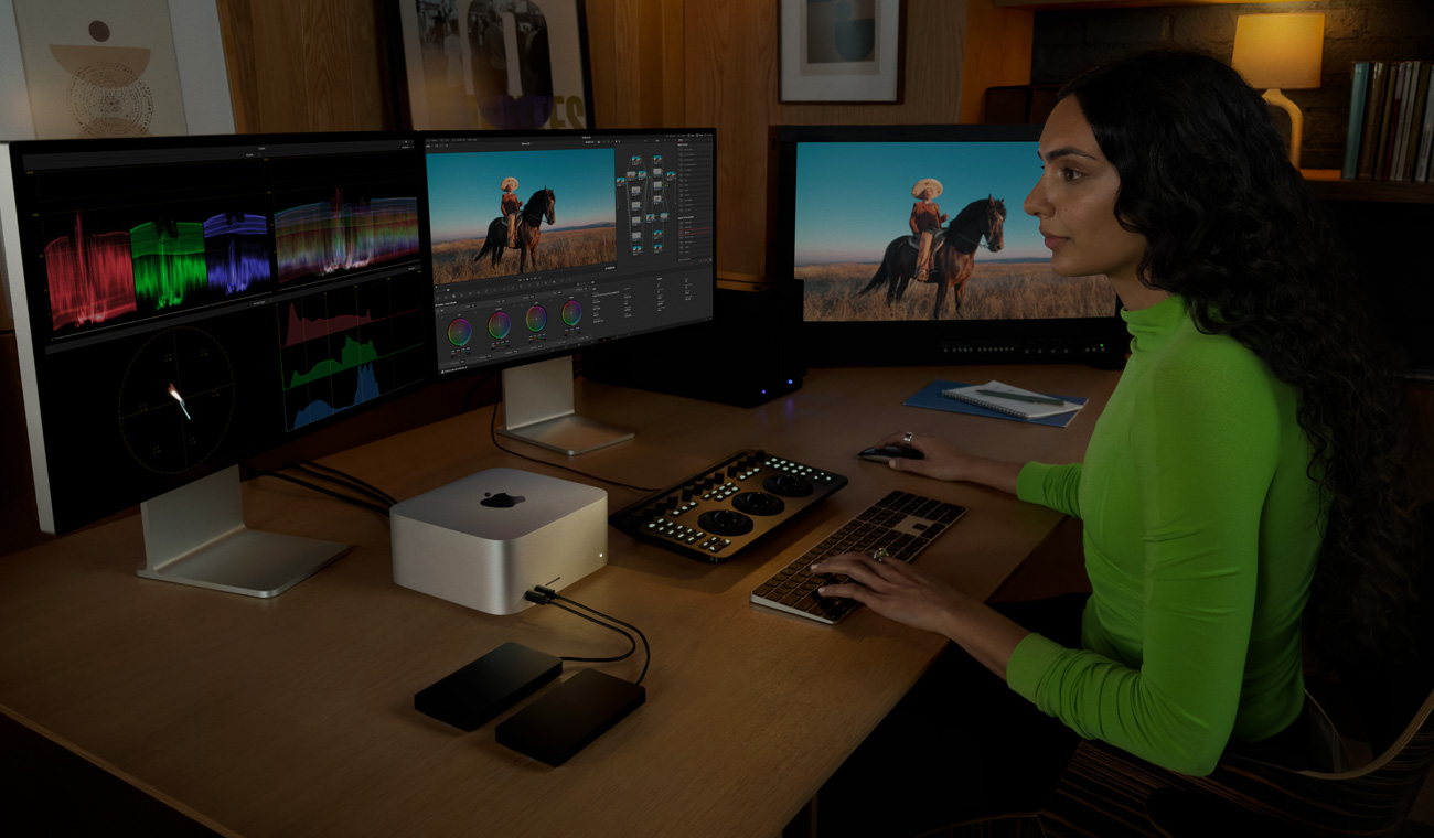 A professional connected to Mac Studio, editing files using three displays