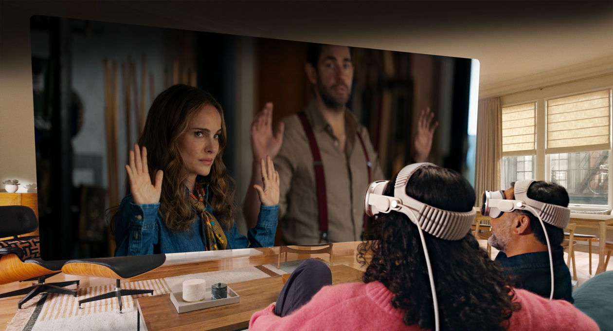 Deux personnes portant un Apple Vision Pro assises côte à côte sur un canapé regardent le film Fountain of Youth sur un écran qui s’étend d’un bout à l’autre de la pièce